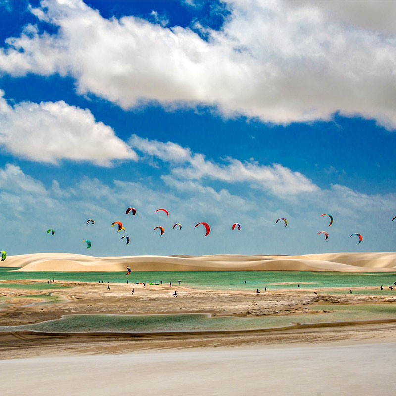 A group of people kitesurfing among the sand dunes of Lençóis Maranhenses