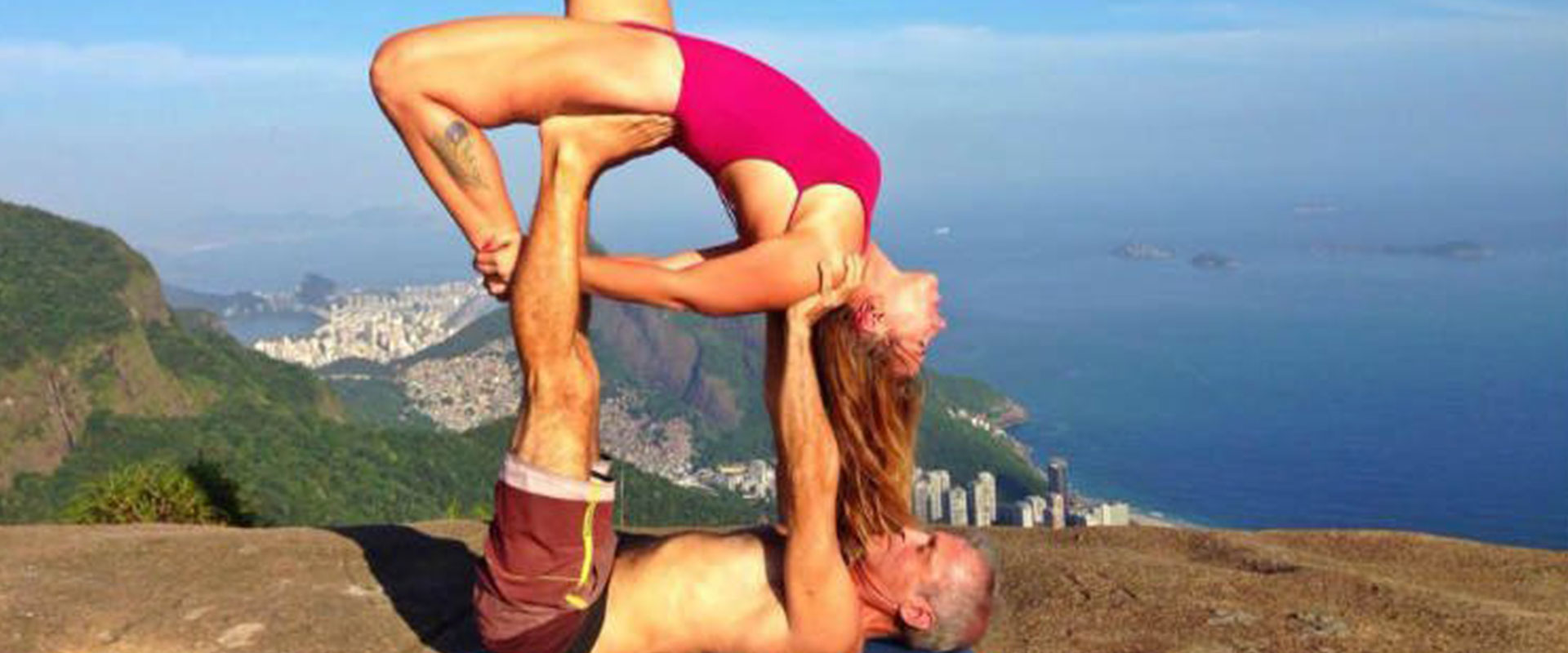 A couple doing a creative yoga pose on top of a mountain