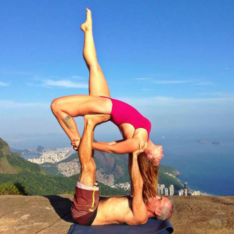 A couple doing a creative yoga pose on top of a mountain