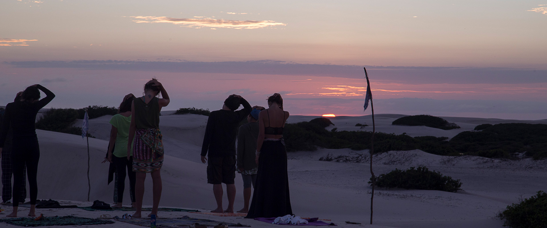 A group of people doing Yoga on the Sand dunes