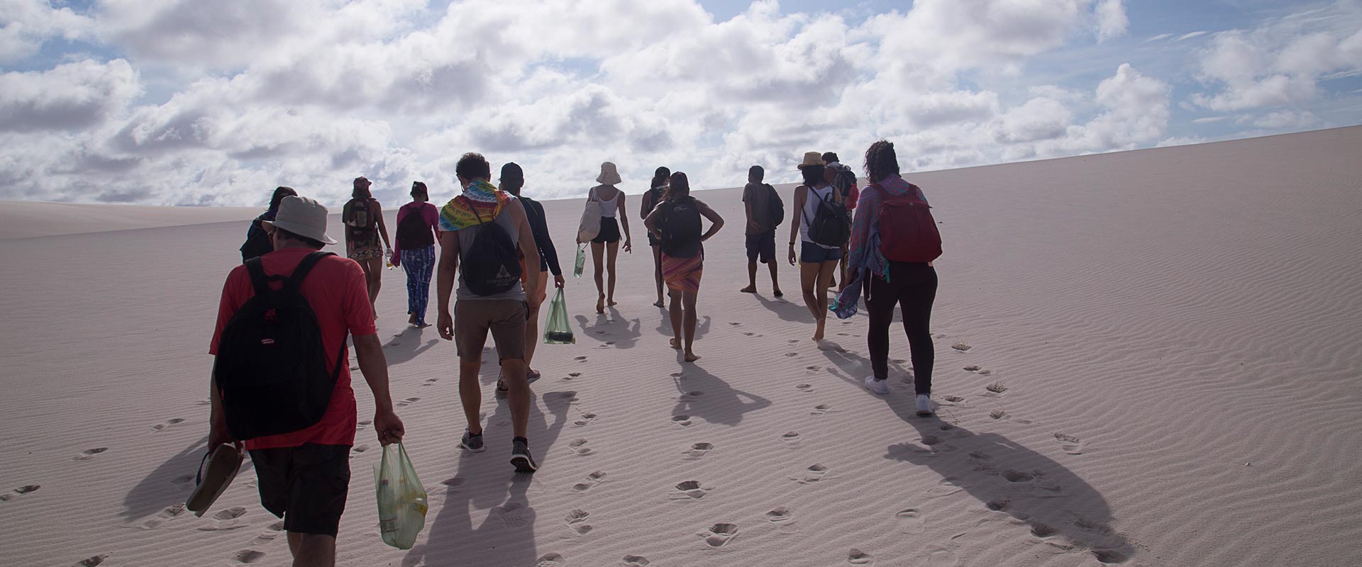 A group of travelers trekking across Lençóis Maranhenses