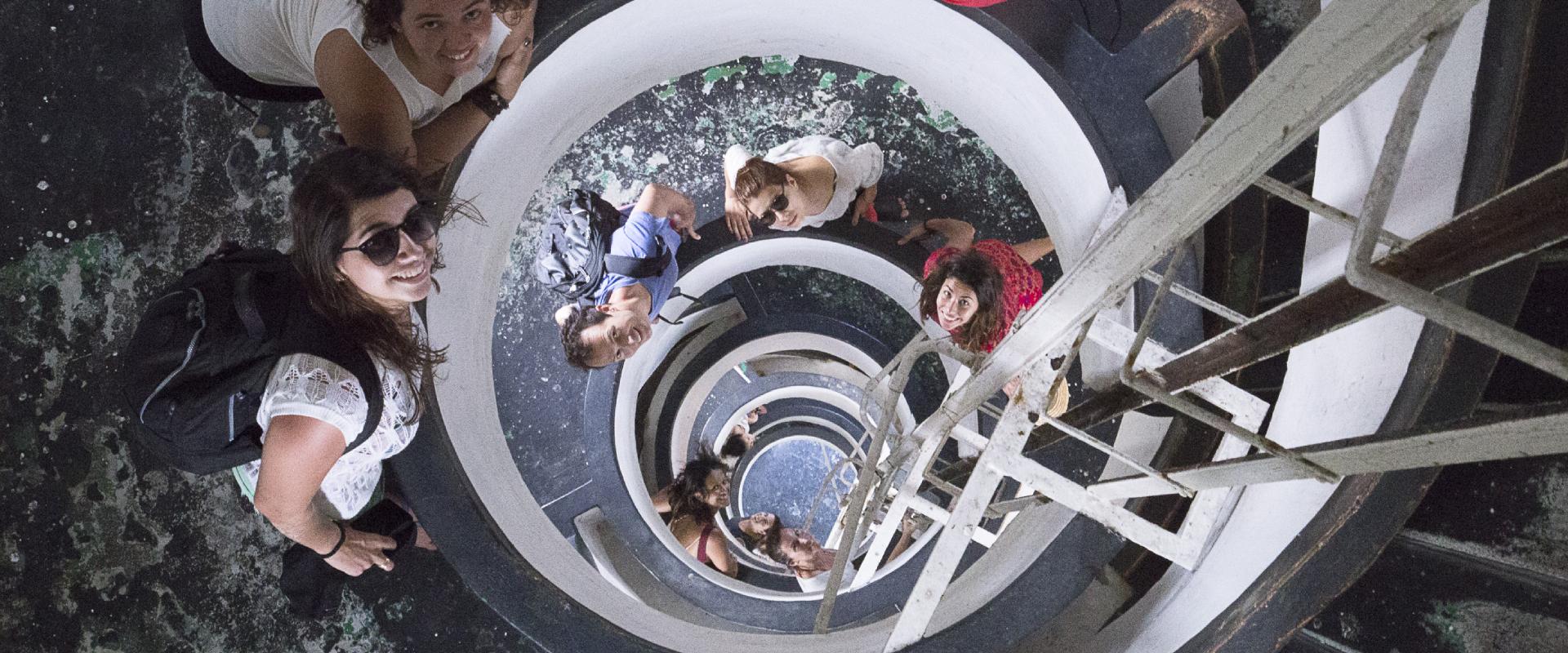 A group of people looking up in a building with a circular staircase