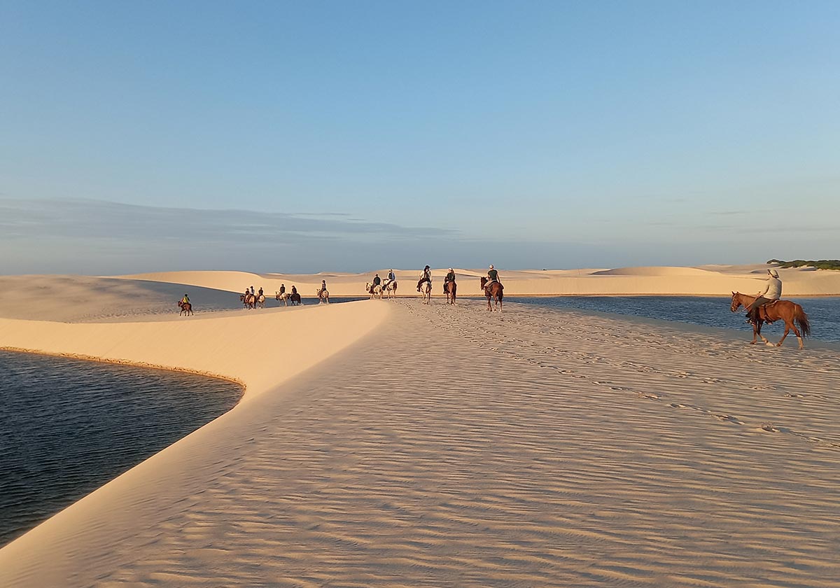 View of tourists horseback riding along the sand dunes of Lençóis Maranhenses