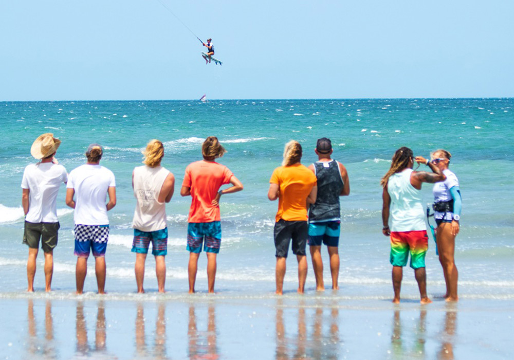 people watching another person kite surf
