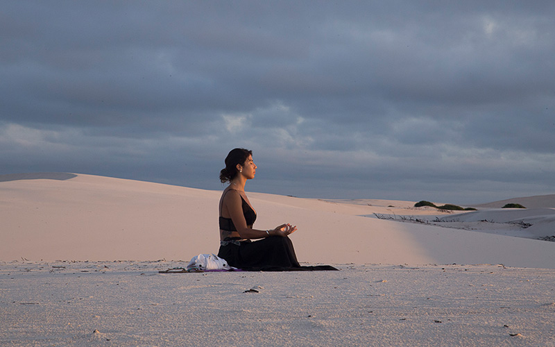 A lady meditating on the sand dunes