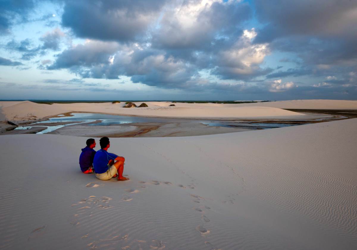 Two people enjoying the view of sand dunes in Atins