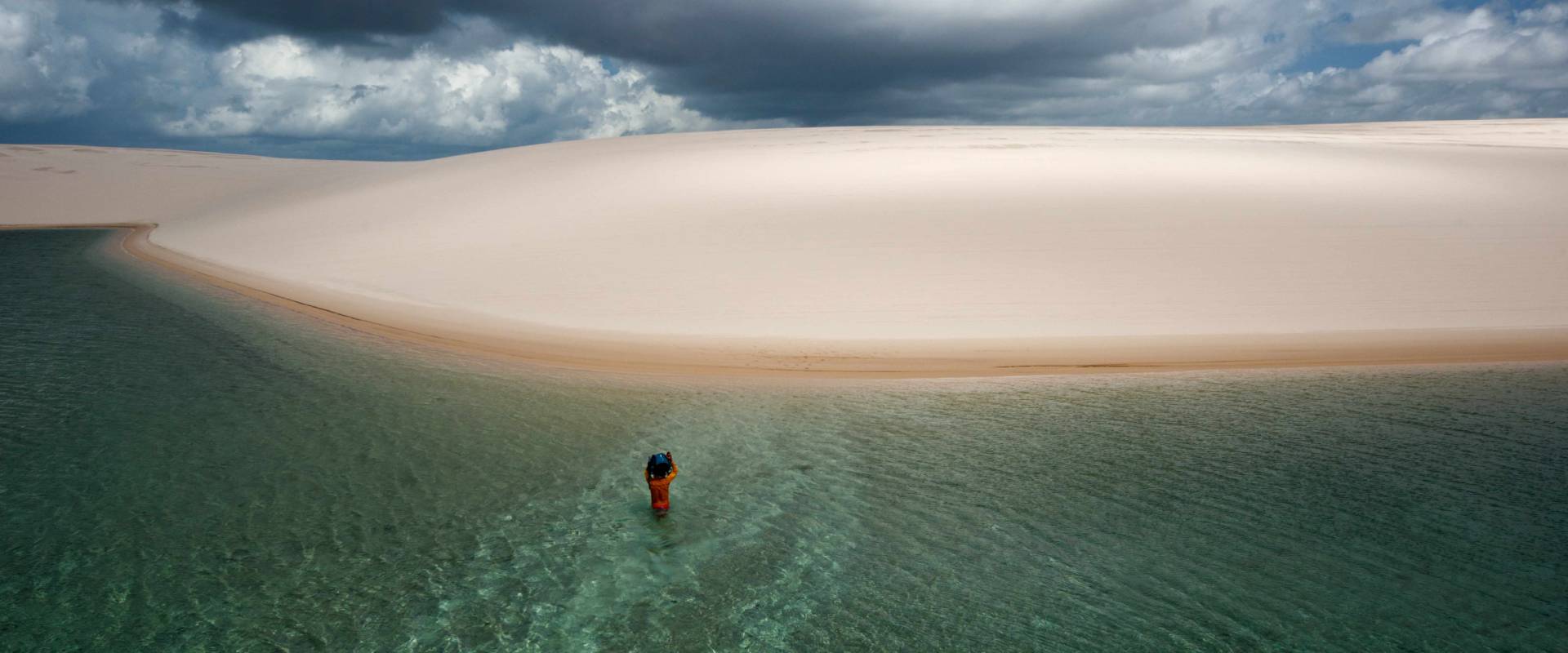 A person taking a dip in a lake among the sand dunes in Atins