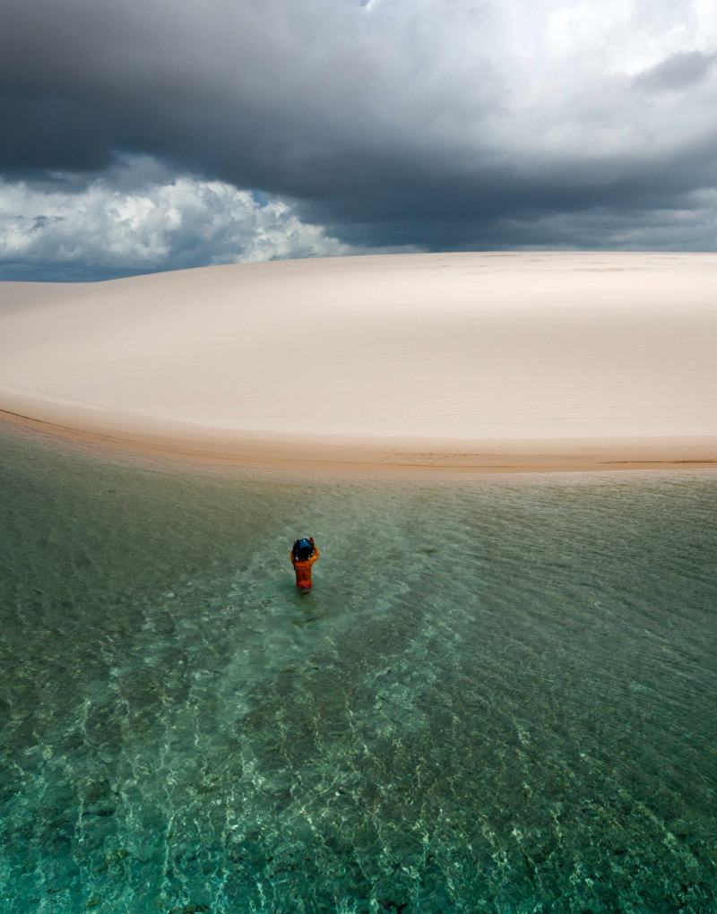 A person taking a dip in the lake among the dunes of Atins